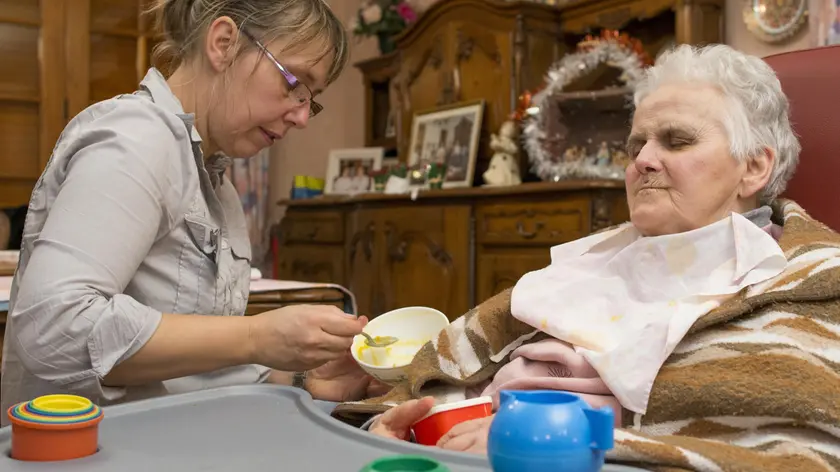 Assistenza ad una anziana. I centri sollievo agordini restano accanto alle famiglie anche ad agosto