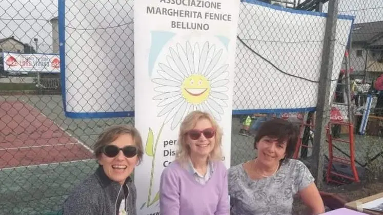 Un banco della Margherita Fenice Belluno: la presidente Virginia Giuffrida, una volontaria, la vice Rosa Vanz