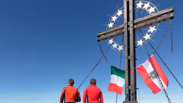 the peak of the mount cavallino (Gr. Kinigat) on the border between Italy and Austria with the cross of Europe and the flags of the two neighboring states, Kartitsch, Carnic alps, Europe