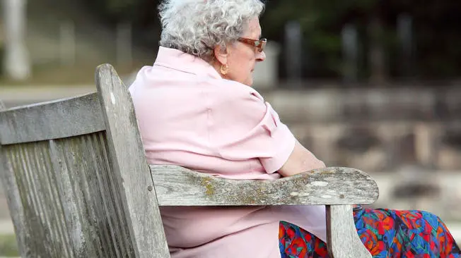 Senior woman sitting on a bench in a public garden