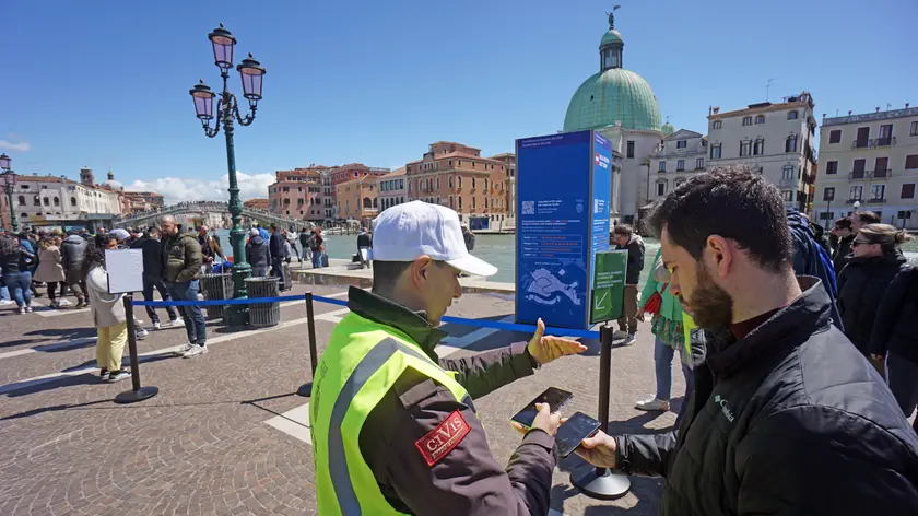 Operatori ai varchi controllano il ticket di accesso sul telefonino dei turisti, al check point del piazzale della stazione ferroviaria di Venezia