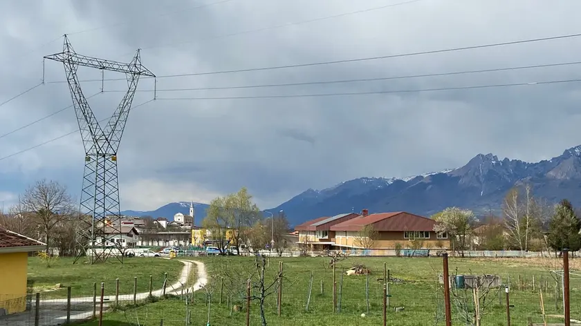 Il traliccio della linea elettrica che attraversa Limana, passando anche vicino alle scuole (a destra nella foto)