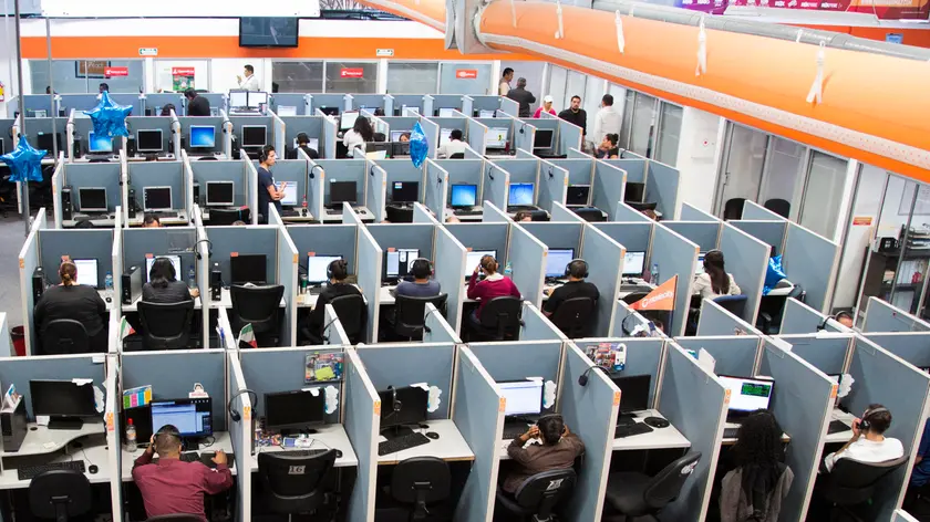 In this Aug. 13, 2014 photo, workers sit at desks at Firstkontact Center, a call center in the northern border city of Tijuana, Mexico.
