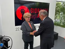 La stretta di mano tra la mamma di Alberto Trentini e il direttore della Mostra del Cinema Alberto Barbera