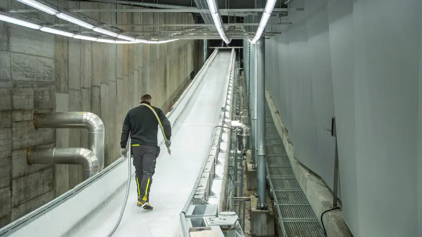 Un ghiacciatore dello sliding centre all'opera lungo il tracciato di Cortina