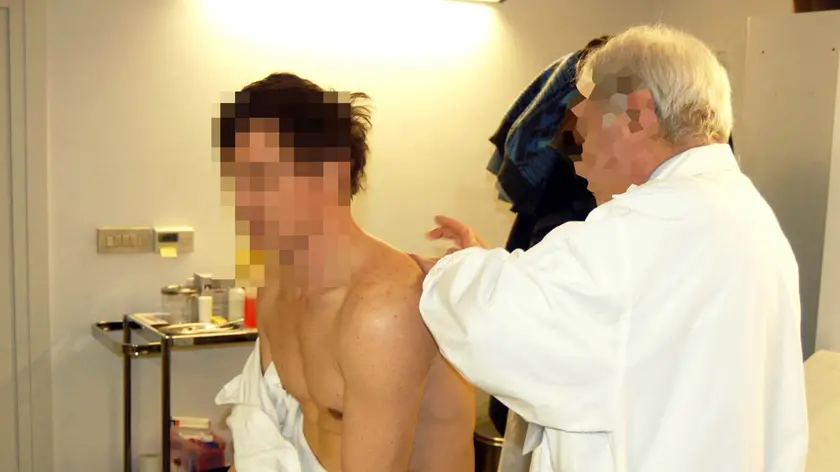 Un medico di medicina generale mentre visita un paziente nel suo ambulatorio