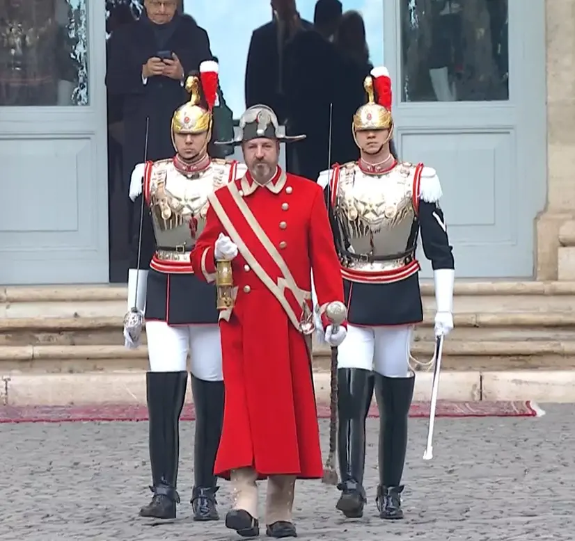 La consegna della fiamma olimpica arrivata in Italia da parte del guardaportone scortato dai Corazzieri