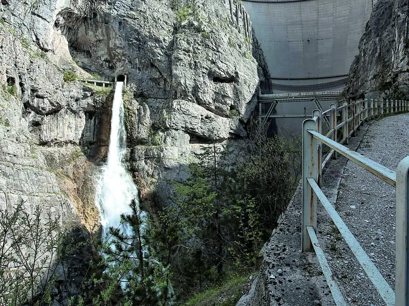 Una veduta della diga del Vajont da valle con la cascata di scarico del by pass e il ponte tubo