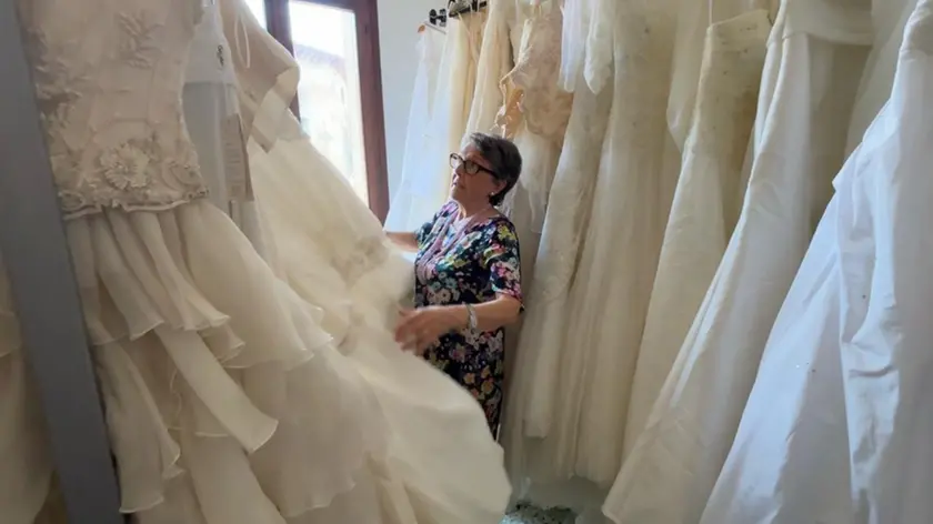 Rosella Lorenzetto, referente della Caritas di Paese, tra gli abiti da sposa dell'Atelier solidale