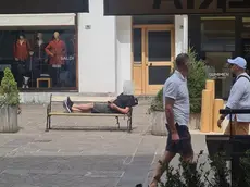 Un turista steso su una panchina a Cortina