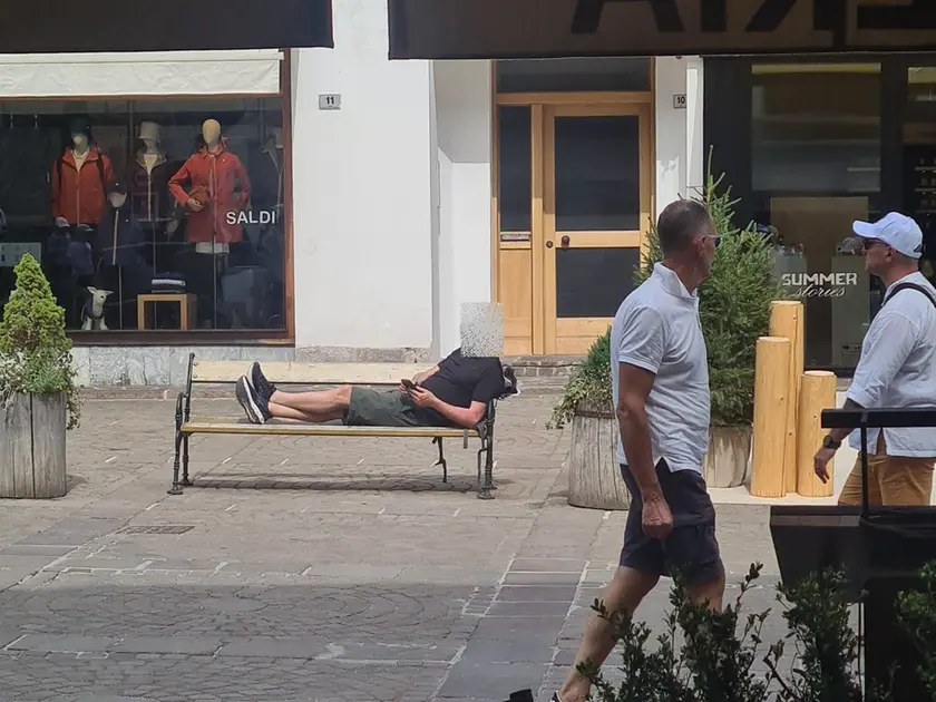 Un turista steso su una panchina a Cortina