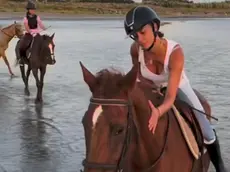 Belen cade da cavallo sulla spiaggia