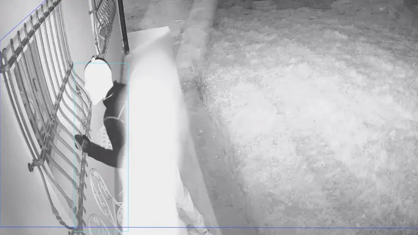 Uno dei due ladri in azione venerdì sera mentre guarda all'interno della villetta dei Bassani attraverso una finestra protetta da una inferriata