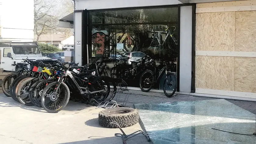 La vetrina anti sfondamento a terra dopo il colpo subito dal negozio Gr Bike di via Rizzarda e il pannello in legno messo per coprire il buco