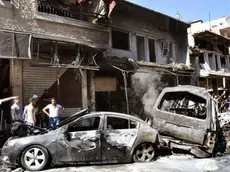 A handout photo made available by Syrian Arab News Agency (SANA) shows citizens inspecting damaged buildings and burnt-out cars at the site of a car bomb explosion in Jaramana residence area in rural Damascus, Syria, 25 July 2013. According to SANA, the explosion caused casualties among citizens. ANSA/SANA HANDOUT HANDOUT EDITORIAL USE ONLY/NO SALES