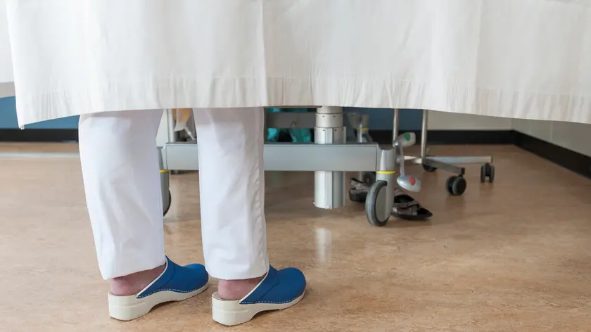 Feet of nurse behind hospital room privacy curtain
