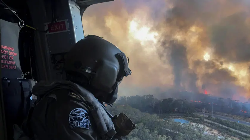 21/12/2019 Blue Mountains, National Park, Nuovo Galles del Sud, nell'area delle Montagne Blu gli incendi continuano a distruggere i boschi causando danni ingenti a persone e animali, nella foto un militare su un elicottero dell'esercito in ricognizione *** Local Caption *** The Australian Defence Force (ADF) is continuing to support Emergency Management Australia in firefighting efforts around the country. Navy’s MRH-90 Taipan helicopters based at HMAS Albatross in Nowra have evacuated residents at risk on the New South Wales South Coast and continue with day and night time aerial fire mapping. An additional MRH-90 forward-deployed to western Sydney, has facilitated access by specialist RFS personnel to properties under threat from advancing fire in the Hartley Vale region. The helicopter was also tasked to support personnel evacuation and property assessment in the Blue Mountains – Lithgow region. ADF liaison officers are working side by side with emergency services personnel in the State Disaster Coordination Centre (SDCC) and within the New South Wales Rural Fire Service Headquarters. Defence is also providing transport and other capabilities such as aviation ground support, logistics, engineering and accommodation to support the firefighting effort.