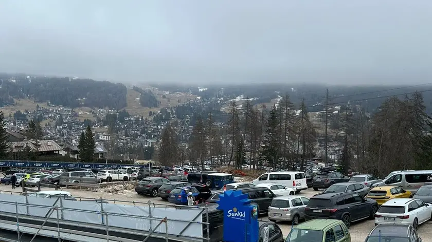 Il parcheggio degli impianti di Socrepes. Sullo sfondo Cortina completamente priva di neve