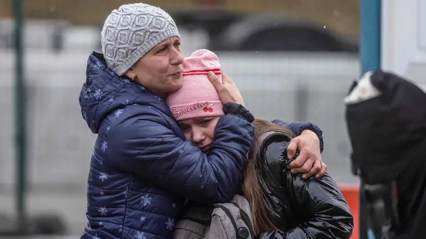 An Ukrainian woman huggs her daughter after acrossing the Ukrainian-Polish border in Korczowa on March 02, 2022. - The number of refugees fleeing the conflict in Ukraine has surged to nearly 875,000, UN figures showed on on March 2, as fighting intensified on day seven of Russia's invasion. (Photo by Wojtek RADWANSKI / AFP)