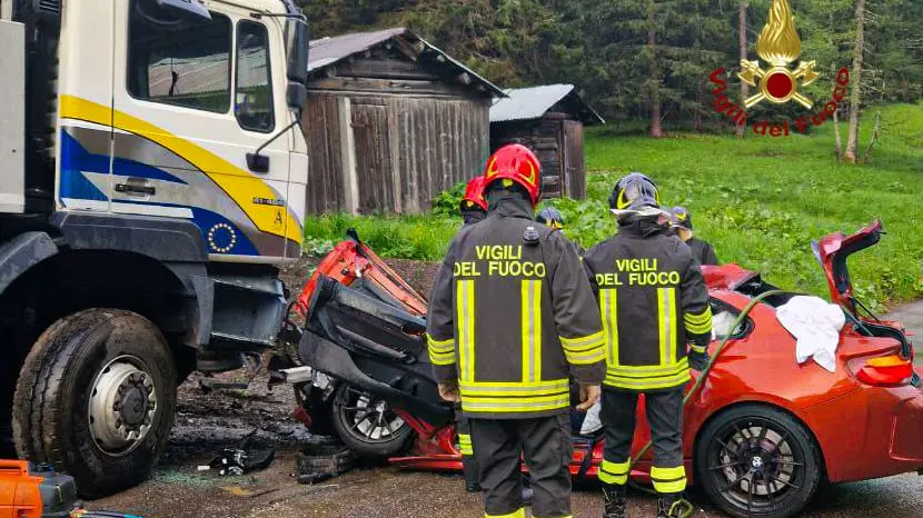 I vigili del fuoco mentre mettono in sicurezza l'auto distrutta contro il camion a Malga Ciapela