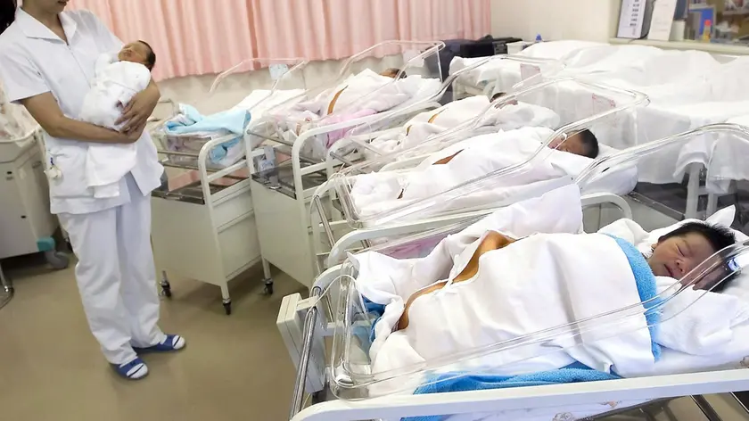 Una infermiera con in braccio un neonato in ospedale in una foto d'ARCHIVIO. ANSA