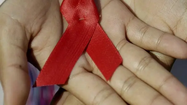 Una donna mostra il nastro rosso simbolo della lotta contro l'Aids in una foto d'archivio. Nel mondo, un numero record di 34 milioni di persone vivono con il virus dell'Hiv. Lo afferma l'ultimo rapporto del Programma congiunto delle Nazioni Unite sull'Hiv/aids (Unaids) da cui emerge, inoltre, che i decessi "sono scesi ai livelli piu' bassi dai picchi registrati dall'epidemia". ANSA/ ULISES RODRIGUEZ