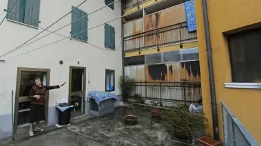 La signora Roberta De Bastiani indica i muri del condominio dell’Ater costruiti 20 anni fa a ridosso della sua casa in barba alle regole sui confini