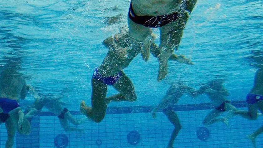 Una partita di pallanuoto in un'immagine d'archivio. Una reazione violenta, incontrollabile e quella che era una sfida sportiva tra ragazzini, una sfida come tante, ha sfiorato la tragedia. E' successo vicino a Roma, a Monterotondo, in una piscina dove si disputava una partita di pallanuoto under 13. Vittima un dodicenne quasi annegato da un coetaneo della squadra avversaria. Adesso il presidente del comitato regionale della Fin, Federazione Italiana Nuoto, Giampiero Mauretti ha trasmesso gli atti al giudice unico regionale Vincenzo Gambardella affinché si approfondisca e si valuti l'aggressione ai danni dell'atleta della Latina Pallanuoto avvenuta nel corso della partita del 20 febbraio scorso contro il Civitavecchia. L'episodio, è scritto nella relazione, si è consumato nella piscina di Monterotondo dove Luca D.G. 12 anni, è stato vittima, nell'ultima parte della gara, di un'aggressione da parte del numero 10 della squadra avversari. L'aggressore ha stretto le mani al collo del ragazzino trattenendolo sott'acqua fino a fargli perdere conoscenza. Due compagni di squadra sono subito intervenuti spingendo la vittima verso l'alto per tirarla fuori dalla vasca. Il 12enne è stato sollevato dalla piscina privo di sensi, con la schiuma bianca che gli usciva dalla bocca e le labbra cianotiche. Il giovane atleta è riuscito a riprendersi ma è rimasto molto scosso. Dal referto medico risultano evidenti graffi sul collo. Kim Ludbrook /ANSA