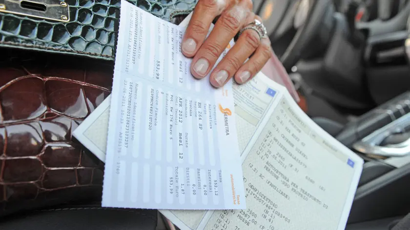 Un bollo e un libretto di circolazione di un'automobile di lusso, fotografati oggi 16 luglio 2011 a Pisa. La manovra economica approvata in tempi ultrarapidi dal Parlamento e' stata pubblica oggi in Gazzetta Ufficiale. Entrano cosi' in vigore da domani le norme modificate non previste dal decreto originario. Da subito scattano i rincari del bollo sul deposito titoli, il superbollo per le auto di lusso sopra i 225 kw, la stretta sulle stock option, l'aumento dell'Irap sulle concessionarie dello Stato e la normativa che potrebbe portare all'applicazione di ticket sanitari. Per altre norme la concreta attuazione segue un diverso calendario: dal prelievo sulle pensioni d'oro, che parte dal primo agosto, al taqlio sulle agevolazioni fiscali che si applichera' dal 2013.ANSA/FRANCO SILVI