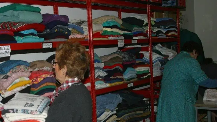 Volontarie della Caritas al lavoro nel centro di distribuzione degli abiti