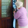 Un anziana che apre la porta a uno sconosciuto