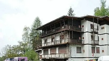 L’albergo San Martino che verrà abbattuto in questi giorni E a destra il grande cartello che sponsorizza il Giro d’Italia che vedrà sul piazzale del Nevegal la conclusione della cronoscalata