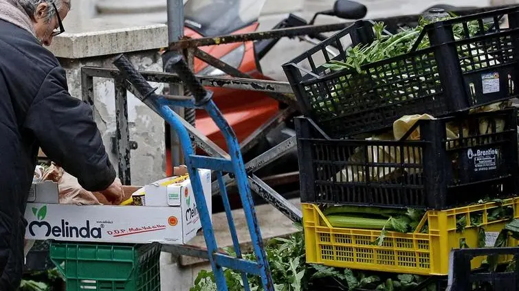 Una donna anziana cerca del cibo tra gli scarti di un mercato, Roma, 20 febbraio 2014. ANSA/ALESSANDRO DI MEO