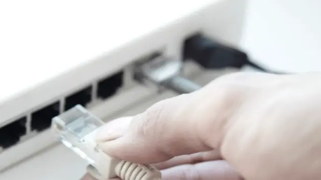 Human hand unplugging computer cable from network hub --- Image by © Arman Zhenikeyev/Corbis