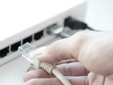 Human hand unplugging computer cable from network hub --- Image by © Arman Zhenikeyev/Corbis