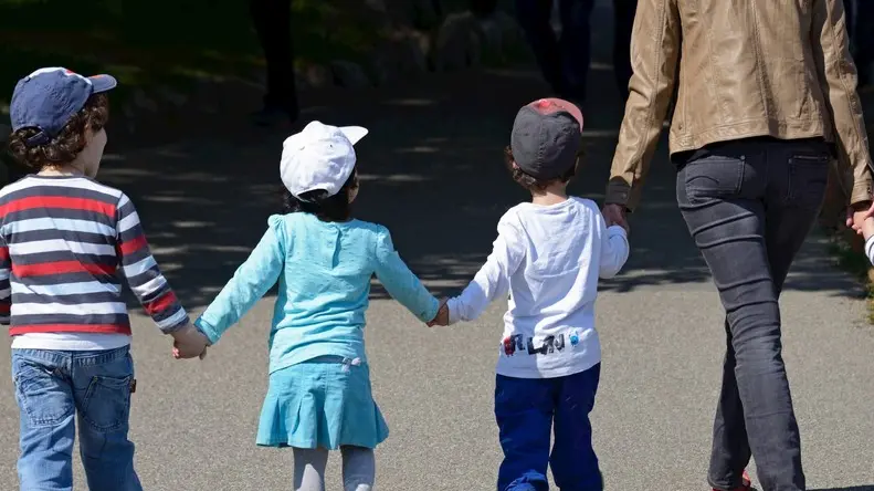 young woman walking hand in hand with four children, Perle du Lac Parc on the shore of Geneva Lake, Geneva, Switzerland