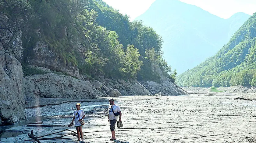 Due turisti a spasso sul lago Del Mis svuotato dagli effetti della laminazione di metà agosto