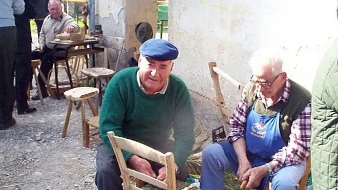 Due impegnati a Mugnai ad impagliare una sedia