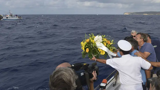 Fishing boat captain Calosero Spalma, wearing white, throws a wreath into the sea to pay tribute to the victims of Thursday's migrant shipwreck off the coast of the southern Italian island of Lampedusa, Saturday, Oct. 5, 2013. A 20-meter boat packed with migrants sank Thursday when the ship capsized after they started a fire to attract attention. Just 155 people survived, 111 bodies have been recovered and more than 200 are still missing. (AP Photo/str)