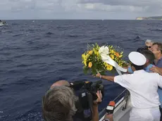 Fishing boat captain Calosero Spalma, wearing white, throws a wreath into the sea to pay tribute to the victims of Thursday's migrant shipwreck off the coast of the southern Italian island of Lampedusa, Saturday, Oct. 5, 2013. A 20-meter boat packed with migrants sank Thursday when the ship capsized after they started a fire to attract attention. Just 155 people survived, 111 bodies have been recovered and more than 200 are still missing. (AP Photo/str)