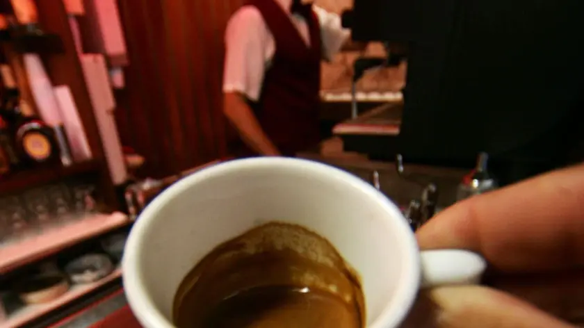 CRISI:CONFCOMMERCIO,-1,8% SPESA 2009,GIU' MOBILI,VESTITI,BAR. Un avventore di un bar mostra una tazzina di caffè. Gli italiani hanno affrontato la crisi economica rinunciando alle spese meno urgenti come le ristrutturazioni e l'acquisto dei beni durevoli in generale ma anche comprimendo gli acquisti di vestiti, alcolici, tabacchi e facendo a meno della pizza al ristorante e del caffe' al bar: e' quando emerge da un Rapporto della Confcommercio sui consumi in Italia negli ultimi 40 anni. ANSA/ CIRO FUSCO/ li