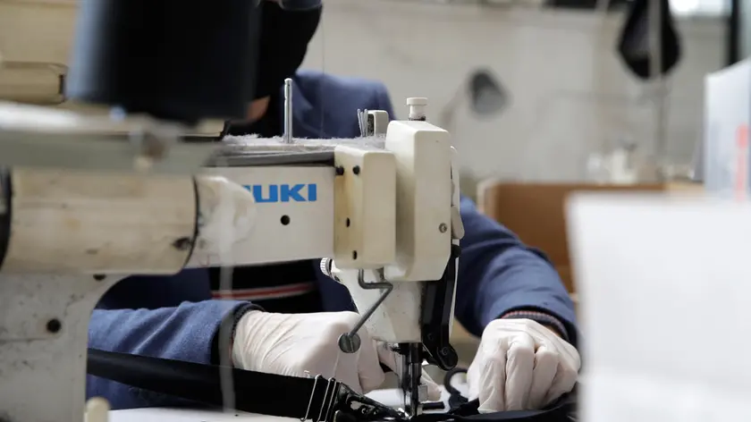 A man works at a sewing machine at DressCode, a garment supplier in the outskirts of Rome, Tuesday, March 31, 2020. After all clients withdrew into quarantine, DressCode re-imagined production making almost 1000 masks a day. Their face masks are not a medical-grade Covid-19 bur are meant as accessories for social distancing. The new coronavirus causes mild or moderate symptoms for most people, but for some, especially older adults and people with existing health problems, it can cause more severe illness or death. (AP Photo/Alessandra Tarantino) .