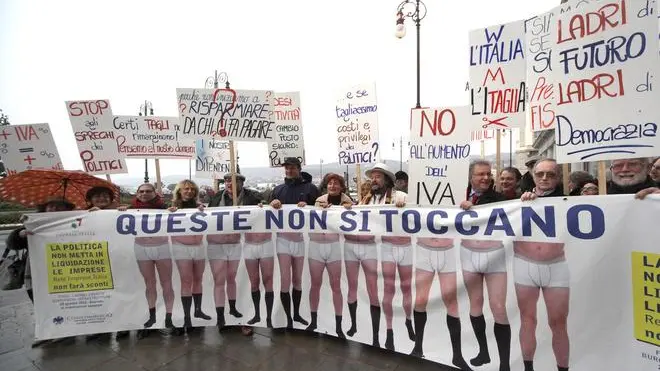 Un gruppo di imprenditori appartenente a Confcommercio, Confartigianato e CNA del Friuli Venezia Giulia espone uno striscione e cartelli di protesta, al termine della manifestazione in occasione della Giornata della Mobilitazione delle Piccole e Medie Imprese a Trieste, 28 gennaio 2013. Nel dossier di 30 pagine di Rete Imprese, presentato dal presidente di turno Carlo Sangalli, al primo punto figura la riduzione della pressione fiscale (in particolare archiviazione Iva, razionalizzazione dell'Irpef, taglio dell'Irap, revisione della riscossione coattiva); rilievo anche al nodo del credito alle imprese, oltre al proseguimento dell'azione di semplificazione, sviluppo del mercato del lavoro (lancio del nuovo apprendistato, sostegno al welfare contrattuale bilaterale, stop a solidarietà impropria tra i settori, con la revisione dei versamenti per l'indennità di malattia a carico di comparti, come commercio e artigianato, il cui tiraggio è basso). ANDREA LASORTE/ANSA