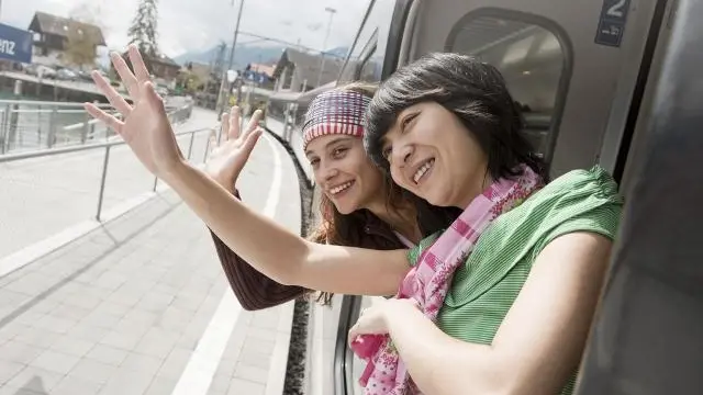 Two women waving out of train window --- Image by © Jesco Tscholitsch/Corbis