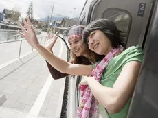 Two women waving out of train window --- Image by © Jesco Tscholitsch/Corbis