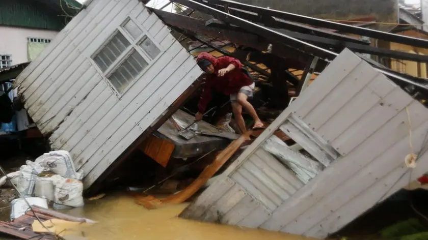 epa04518370 A Filipino resident collects belongings on a damged house in Borongan city, Samar island, Philippines, 07 December 2014. Typhoon Hagupit knocked out power and flattened houses as it pummeled the eastern and central Philippines overnight, leaving millions of people in darkness amid heavy rains and howling winds, officials said. Communication was also cut off in some of the affected areas as Hagupit slammed into the coastal town of Dolores in Eastern Samar province on Saturday evening, toppling trees and ripping off rooftops. There were no early reports of casualties, but authorities said they were still gathering information on the ground. EPA/FRANCIS R. MALASIG
