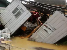 epa04518370 A Filipino resident collects belongings on a damged house in Borongan city, Samar island, Philippines, 07 December 2014. Typhoon Hagupit knocked out power and flattened houses as it pummeled the eastern and central Philippines overnight, leaving millions of people in darkness amid heavy rains and howling winds, officials said. Communication was also cut off in some of the affected areas as Hagupit slammed into the coastal town of Dolores in Eastern Samar province on Saturday evening, toppling trees and ripping off rooftops. There were no early reports of casualties, but authorities said they were still gathering information on the ground. EPA/FRANCIS R. MALASIG